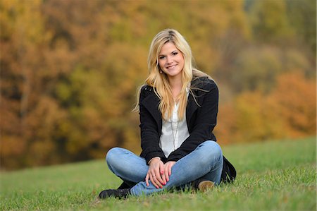 Blonde junge Frau in herbstlicher Wiese sitzt lächelnd Stockbilder - Lizenzpflichtiges, Bildnummer: 853-06442246