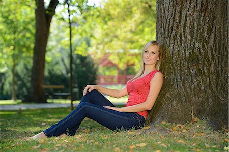 Young blond woman at a tree trunk in a park Stock Photo - Rights-Managed, Code: 853-07241818