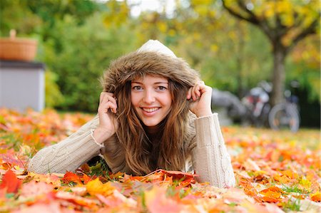 simsearch:853-07148641,k - Smiling young woman lying in autumn leaves Stock Photo - Rights-Managed, Code: 853-07241911