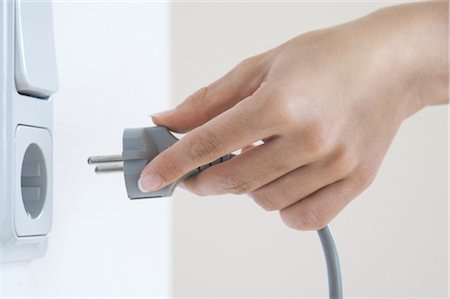 energy source - Womans hand doing plug in socket, close-up Foto de stock - Con derechos protegidos, Código: 853-02914259