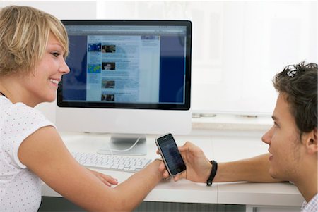 slim teens - Two teenager changing phone numbers in internet cafe, side view Stock Photo - Rights-Managed, Code: 853-03458840