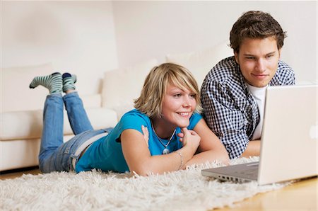 Teenager couple lying on carpet, watching media on notebook, low-angle view Foto de stock - Con derechos protegidos, Código: 853-03458861