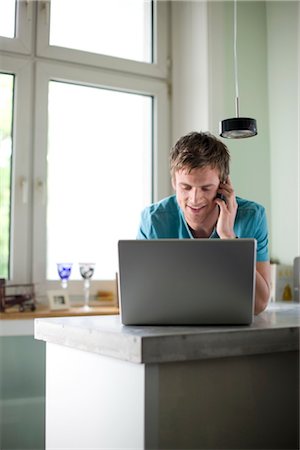 simsearch:853-03458862,k - Young man standing at a counter and using mobile phone and laptop, low angle view Stock Photo - Rights-Managed, Code: 853-03459128