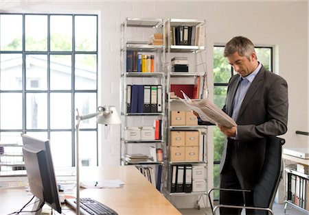 Homme lisant un journal dans un bureau Photographie de stock - Rights-Managed, Code: 853-03459130