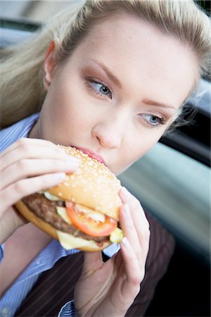 eating burger - Businesswoman eating a hamburger, close-up Stock Photo - Rights-Managed, Code: 853-03459149