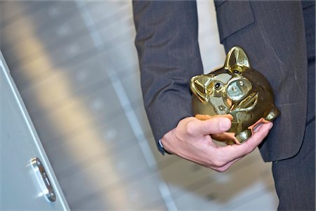 saving piggy bank - Man in front of safe deposit boxes holding golden piggy bank, close-up Stock Photo - Rights-Managed, Code: 853-03616794