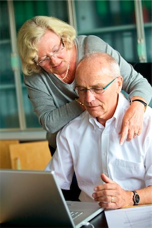senior couple computer not smiling - Senior woman embracing man at desk Stock Photo - Rights-Managed, Code: 853-03616931