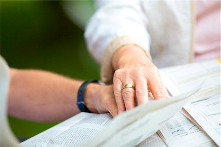 Senior couple reading newspaper hand in hand, close-up Foto de stock - Con derechos protegidos, Código: 853-03616993