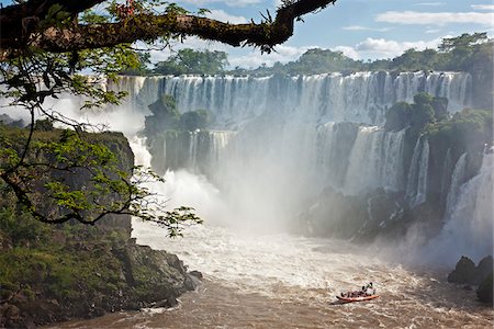An inflatable boat takes visitors into white water at the bottom of one of the spectacular Iguazu Falls of the Iguazu National Park, a World Heritage Site. Argentina Foto de stock - Con derechos protegidos, Código: 862-05996711