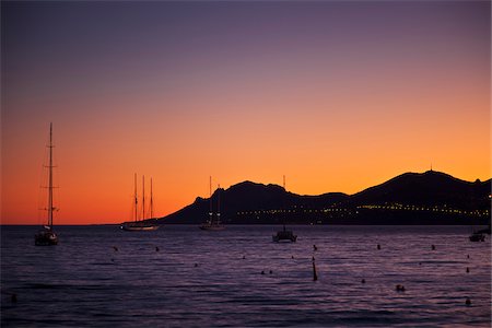 exclusivo - Cannes,  Provence-Alpes-Cote d'Azur, France. View looking towards Theoule Sur Mer from Cannes at sunset with yachts moored in the bay Foto de stock - Con derechos protegidos, Código: 862-05997639