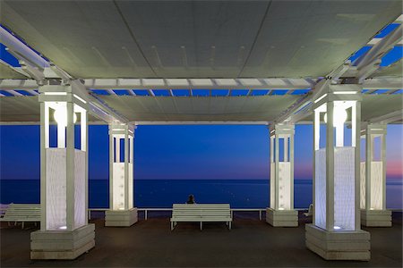 simsearch:862-05997674,k - Saint Philippe, Nice, Provence Alpes Cote d'Azur, France. Canopies over the Promenade Des Anglais with single woman on a bench, Nice at sunset Foto de stock - Con derechos protegidos, Código: 862-05997655