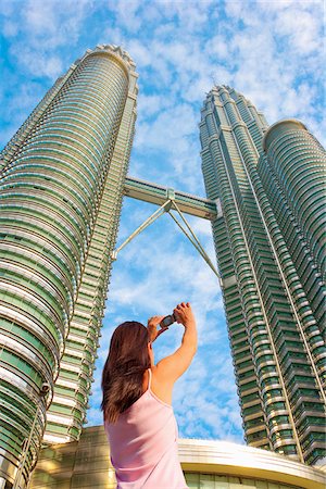 simsearch:700-03805307,k - Malaysia, Kuala Lumpur, Petronas Towers, Woman photographing towers Foto de stock - Con derechos protegidos, Código: 862-05998548