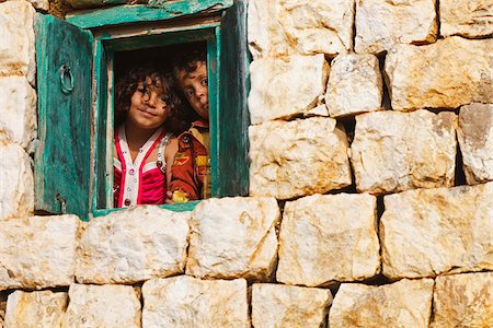 Yemen, Sana'a Province, Haraz Mountains, Al Hajjarah. Children looking through the window of their home. Foto de stock - Con derechos protegidos, Código: 862-05999726