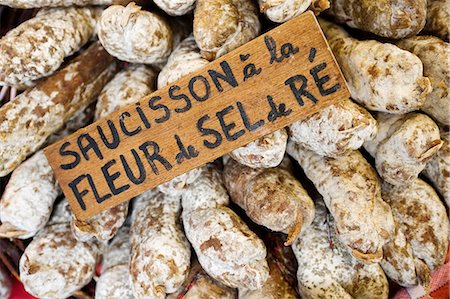 saucisson - France, Charente Maritime, Ile de Re.  Saucisson or whole salamis dusted with salt harvested from the salt flats on the Ile de Re, on a market stall in Les Portes. Stock Photo - Rights-Managed, Code: 862-06541467