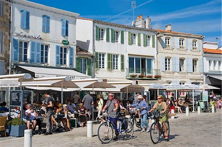 France, Charente Maritime, Ile de Re.  Tourists eat at tables set outside the cafes and restaurants that overlook the small harbour in La Flotte. Foto de stock - Con derechos protegidos, Código: 862-06541469