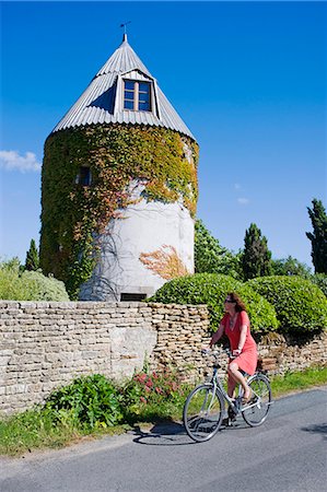 simsearch:862-06541450,k - France, Charente Maritime, Ile de Re.  A tourist cycles past an old windmill now converted into a house on the outskirts of Les Portes. MR Stockbilder - Lizenzpflichtiges, Bildnummer: 862-06541462