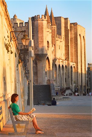 France, Provence, Avignon, Palais de Papes, Woman reading book on bench MR Stock Photo - Rights-Managed, Code: 862-06541508