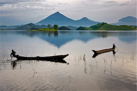 Young boys fish from dugout canoes on Lake Mutanda with its stunning backdrop of the Virunga Volcanoes, Uganda, Africa Photographie de stock - Rights-Managed, Code: 862-06543264