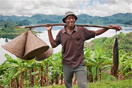 A jovial fisherman with fishing baskets and his catch of the day, which he caught in Lake Mutanda, Uganda, Africa Stock Photo - Rights-Managed, Code: 862-06543269