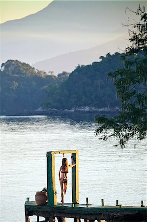 simsearch:862-06677430,k - Angra dos Reis; Green Coast, Costa Verde, Ilha Grande, a model stands in an arch on the end of a pier at dawn Foto de stock - Con derechos protegidos, Código: 862-06675712