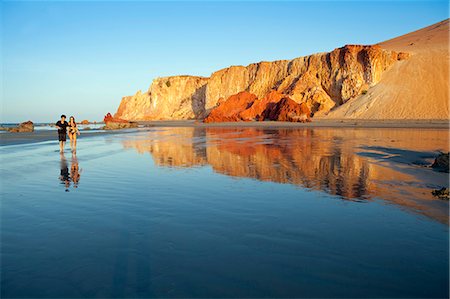 simsearch:862-06675755,k - South America, Brazil, Ceara, Morro Branco,a couple walk along a long sandy beach between the Atlantic and the red sand dunes and cliffs at Morro Branco Foto de stock - Con derechos protegidos, Código: 862-06675747