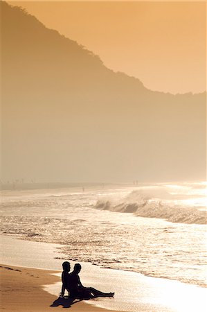 South America, Rio de Janeiro, Rio de Janeiro city, a gay couple silhouetted against in golden light, sit on the sand on Copacabana Beach with Copacabana and the Morro do Leme hill in the background Stockbilder - Lizenzpflichtiges, Bildnummer: 862-06675800