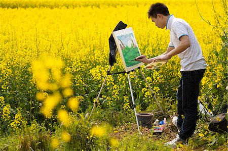 China, Yunnan, Luoping. A young artist hard at work in the mustard fields at Luoping. Stock Photo - Rights-Managed, Code: 862-06676197