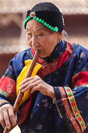 robe (draped garment) - China, Yunnan, Liuyi. Lady playng a Chinese flute in the village of Liuyi. Stock Photo - Rights-Managed, Code: 862-06676250