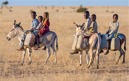 donkeys africa - Chad, Biltine, Oum-Chelouba, Sahel. Children return home on donkeys after collecting water from a deep well. Photographie de stock - Rights-Managed, Code: 862-06676389