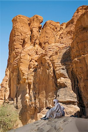 simsearch:862-06676493,k - Chad, Elikeo, Ennedi, Sahara. Two Toubou tribesmen rest in the shadow of a large weathered sandstone feature. Fotografie stock - Rights-Managed, Codice: 862-06676424