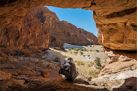 Chad, Elikeo, Ennedi, Sahara. A Toubou man looks out of a massive sandstone cave. Photographie de stock - Rights-Managed, Code: 862-06676420