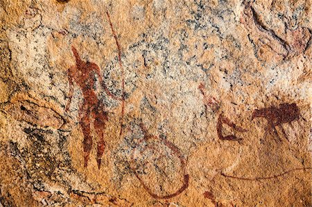 Chad, Guili Dweli, Ennedi, Sahara. A rock painting of two men and a cow, one man with a long curved stick or lance, the other running. Stock Photo - Rights-Managed, Code: 862-06676436