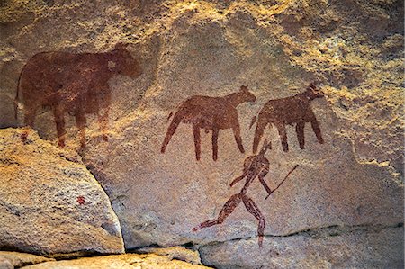 painting (work of art) - Chad, Taore Koaole, Ennedi, Sahara. A painting of cattle and a man running with a stick or club in hand decorate the sandstone wall of a cave. Stock Photo - Rights-Managed, Code: 862-06676444