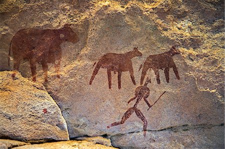 petroglyphs - Chad, Taore Koaole, Ennedi, Sahara. A painting of cattle and a man running with a stick or club in hand decorate the sandstone wall of a cave. Stock Photo - Rights-Managed, Code: 862-06676444