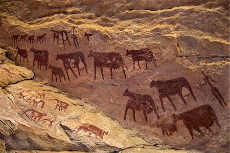 petroglyph - Chad, Taore Koaole, Ennedi, Sahara. Bichrome paintings of cattle and two human figures decorate the sandstone wall of a cave. Stock Photo - Rights-Managed, Code: 862-06676442