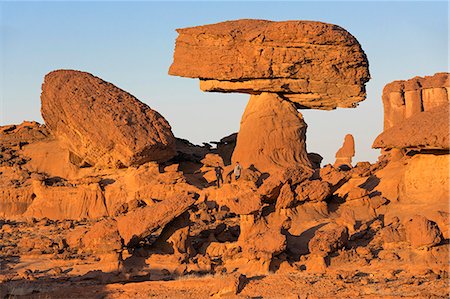 simsearch:862-06676480,k - Chad, Chigeou, Ennedi, Sahara. A ridge of weathered red sandstone with two visitors giving scale to the giant mushroom-like feature. Foto de stock - Con derechos protegidos, Código: 862-06676497