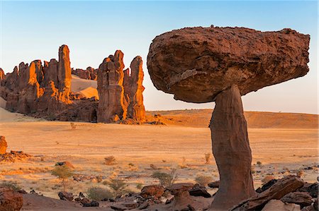 Chad, Chigeou, Ennedi, Sahara. Weathered red sandstone in a desert landscape with a large mushroom-like feature of balancing rock. Photographie de stock - Rights-Managed, Code: 862-06676499