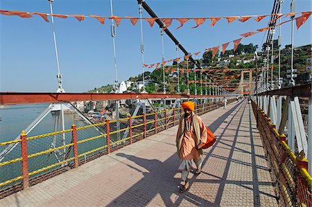 India, Madhya Pradesh, Omkareshwar. A Hindu pilgrim crosses a bridge at Omkareshwar, a sacred island in the Narmada River and an important pilgrimage destination. Stock Photo - Rights-Managed, Code: 862-06676817