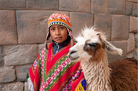 perú - South America, Peru, Cusco. A Quechua boy in a poncho and a chullo woollen cap with a Llama standing in front of an Inca wall in the UNESCO World Heritage listed former Inca capital of Cusco Foto de stock - Con derechos protegidos, Código: 862-06677339
