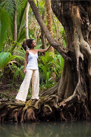 Dominica, Portsmouth. A young woman stands on a tree on the Indian River, one of Dominica's most popular tourist attractions. (MR). Stock Photo - Rights-Managed, Code: 862-06825260