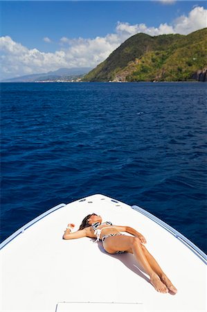 Dominica, Soufriere. A young woman sunbathes on the foredeck of a Powerboat near Soufriere. (MR). Stock Photo - Rights-Managed, Code: 862-06825276