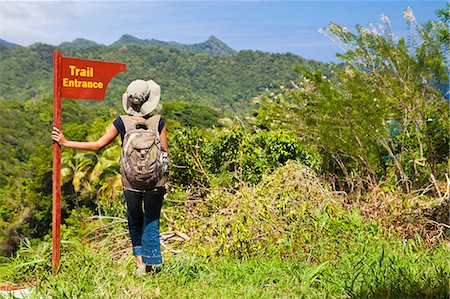 Dominica, Riviere Cyrique. A young woman stands by a sign at the start of the trail to Wavine Cyrique. (MR). Stock Photo - Rights-Managed, Code: 862-06825301