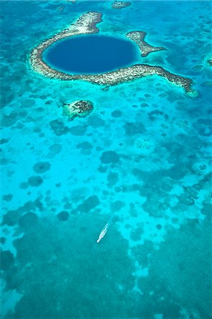 Central America, Belize, Lighthouse atoll, the Great Blue Hole, aerial shot of a dive boat leaving the Blue Hole. The hole is a marine cenote - a sunken cave in the Lighthouse atoll, part of the World Heritage listed Belize Barrier Reef System Fotografie stock - Rights-Managed, Codice: 862-07495816