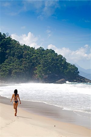 South America, Brazil, Green Coast (Costa Verde), Sao Paulo, Ubatuba, view of a model walking along Felix beach, with a spur of unesco-protected South-East Reserves Atlantic Forest stretching down to the sand in the distance (MR) Foto de stock - Direito Controlado, Número: 862-07495826