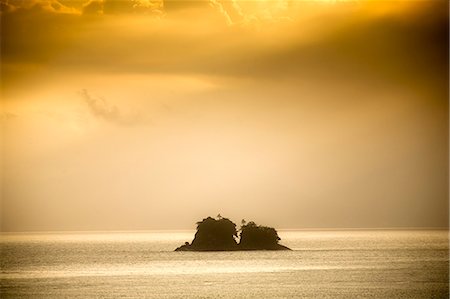 South America, Brazil, Green Coast (Costa Verde), Sao Paulo, Ubatuba, two tiny islands silhoutted against a golden sunset Foto de stock - Direito Controlado, Número: 862-07495831