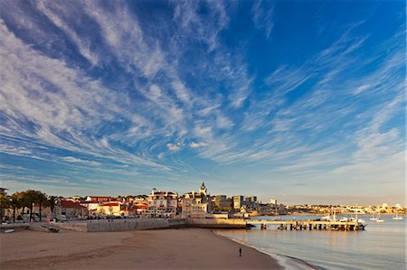 Praia dos Pescadores (Fisherman's Beach) with  the Capitania Porto (The Port Authority) and the towns of Cascais and Monte Estoril in the background at sunset,Cascais, Abuxarda, Lisbon, Lisboa, Portugal. Photographie de stock - Rights-Managed, Code: 862-07496246