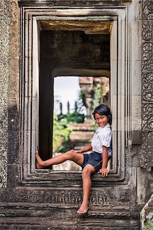 Cambodia, Banteay Samrei, Siem Reap Province. A young Cambodian girl sits in a window of the 12th century Hindu temple of Banteay Samre. Stock Photo - Rights-Managed, Code: 862-07689874