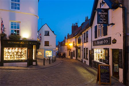 shops on a cobblestone street - United Kingdom, England, North Yorkshire, Whitby. Dusk on Chruch Street. Stock Photo - Rights-Managed, Code: 862-07689987