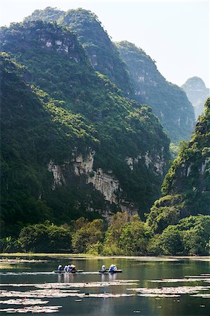 Vietnam, Ninh Binh Province, Tam Coc. Karst limestone mountains tower above visitors boating on a stretch of the Ngo Dong River. Foto de stock - Con derechos protegidos, Código: 862-07690969