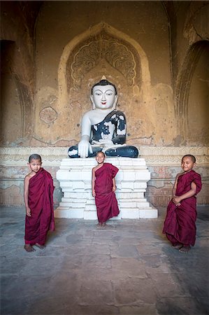 simsearch:862-03807977,k - Myanmar, Mandalay division, Bagan. Three novice monks inside a pagoda near a Buddha statue (MR) Stock Photo - Rights-Managed, Code: 862-07910316